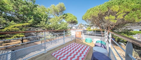 A wooden deck with a chevron-patterned rug, metal railings, and outdoor seating.