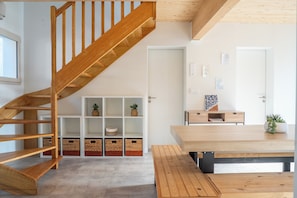 Ein modernes Interieur mit einer Holztreppe, einer weißen Wand mit Kunstwerken und einem Holzesstisch.