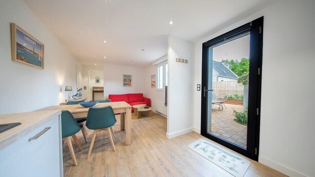 Ein modernes Interieur mit Essbereich, einem roten Sofa und einer Schiebeglastür, die auf eine Terrasse führt.