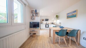 Eine moderne Küche mit Fernseher, Esstisch und Stühlen.