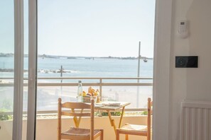 Ein Balkon mit Tisch und Stühlen, mit Blick auf ein Gewässer und Boote.