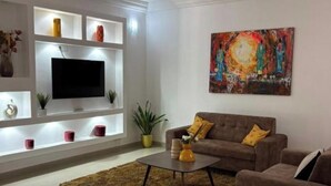 Una sala de estar moderna con una televisión de pantalla plana, un sofá, una mesa de centro y un cuadro en la pared.