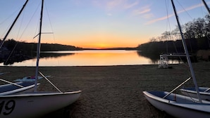A calm lake at sunset with boats on the shore.