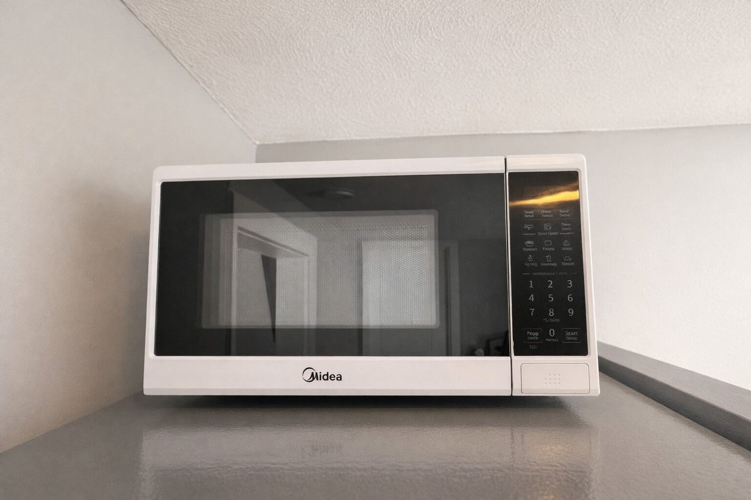 A white microwave oven with a digital display and control panel, placed on a countertop.
