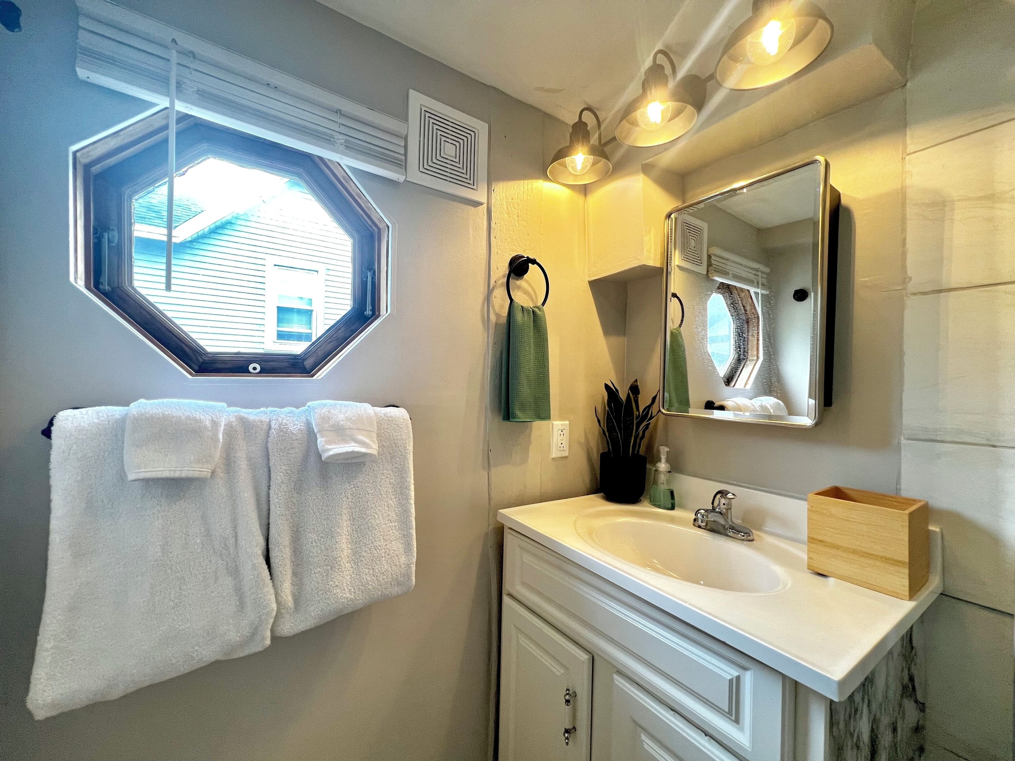 A bathroom with a large mirror, a window, and a towel rack.