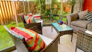 Un espace patio aménagé avec des meubles en osier, une table et une vue sur un jardin.