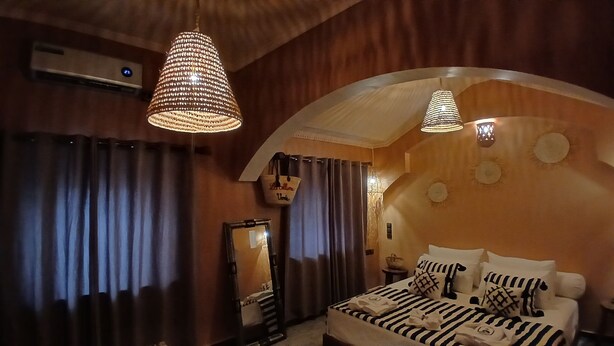 A bedroom with a bed, curtains, a hanging basket, and a mirror. - La Colline Verte Dar Ait El Abass  (Skoura)