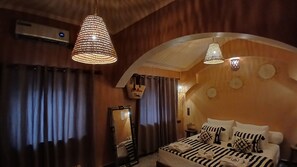 A bedroom with a bed, curtains, a hanging basket, and a mirror.