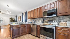 A modern kitchen with wooden cabinets, granite countertops, stainless steel appliances, and a backsplash. - Heated Pool & SPA Retreat+Gameroom+ Beaches+IMG (Bradenton)