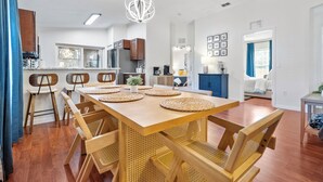 A modern kitchen with wooden cabinets, a dining area with a wooden table and chairs, and a living area with a sofa and a coffee table. - Heated Pool & SPA Retreat+Gameroom+ Beaches+IMG (Bradenton)