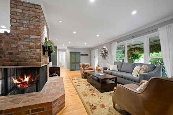 Una sala de estar con chimenea de ladrillo, un sofá, un sillón y una mesa de centro.