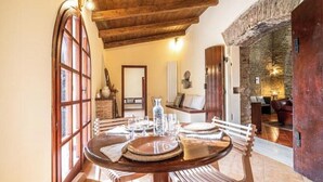 A dining area with a round table set for four, wooden chairs, a vase, and a bottle. - Corte San Pastore - Boutique Location di Charme Senza Tempo (Tivoli)
