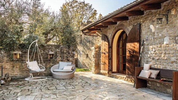 A stone patio with a hanging chair, a cushioned seating area, and a wooden bench. - Corte San Pastore - Boutique Location di Charme Senza Tempo (Tivoli)
