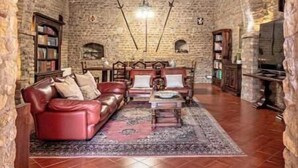 A stone-walled room with a fireplace, leather sofa, and a chandelier. - Corte San Pastore - Boutique Location di Charme Senza Tempo (Tivoli)