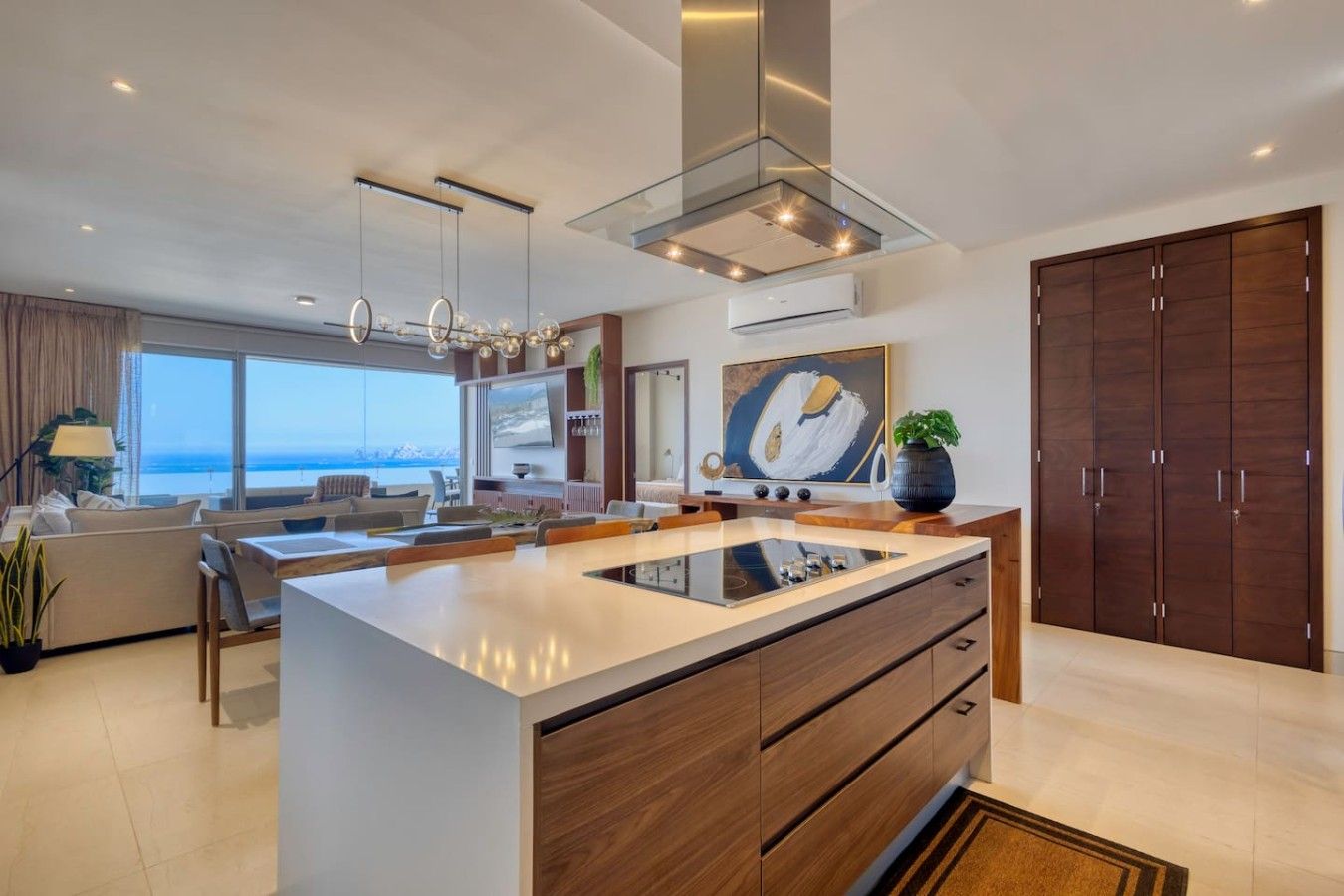 Une cuisine moderne dotée d’un îlot central, de placards intégrés et d’une grande fenêtre donnant sur la mer.