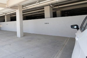 A parking garage with concrete pillars and a white wall with the number 3203. - Casa Oasis - Upscale 3B/3B condo (Cabo San Lucas)