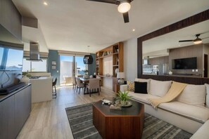 Een moderne woonkamer met een bank, salontafel en een eethoek met stoelen.
