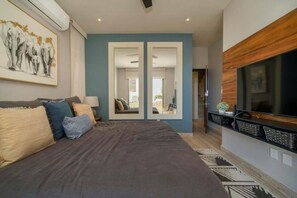 Een slaapkamer met een groot bed, een televisie en een spiegel.