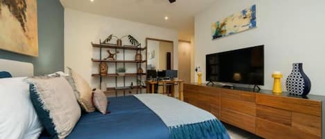 Un dormitorio moderno con cama, televisor, cómoda de madera y ventilador de techo.