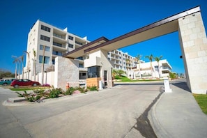 Een meerlaags hotel met een modern ontwerp, met een overdekte ingang en een parkeerplaats met een rode auto.