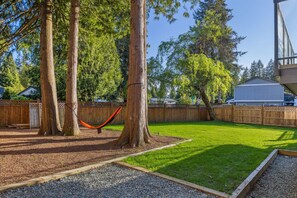 A backyard with a hammock, trees, a wooden fence, and a well-maintained lawn. - Bunny Bliss - Lower Level, HotTub, FirePit,Theatre (Langley)
