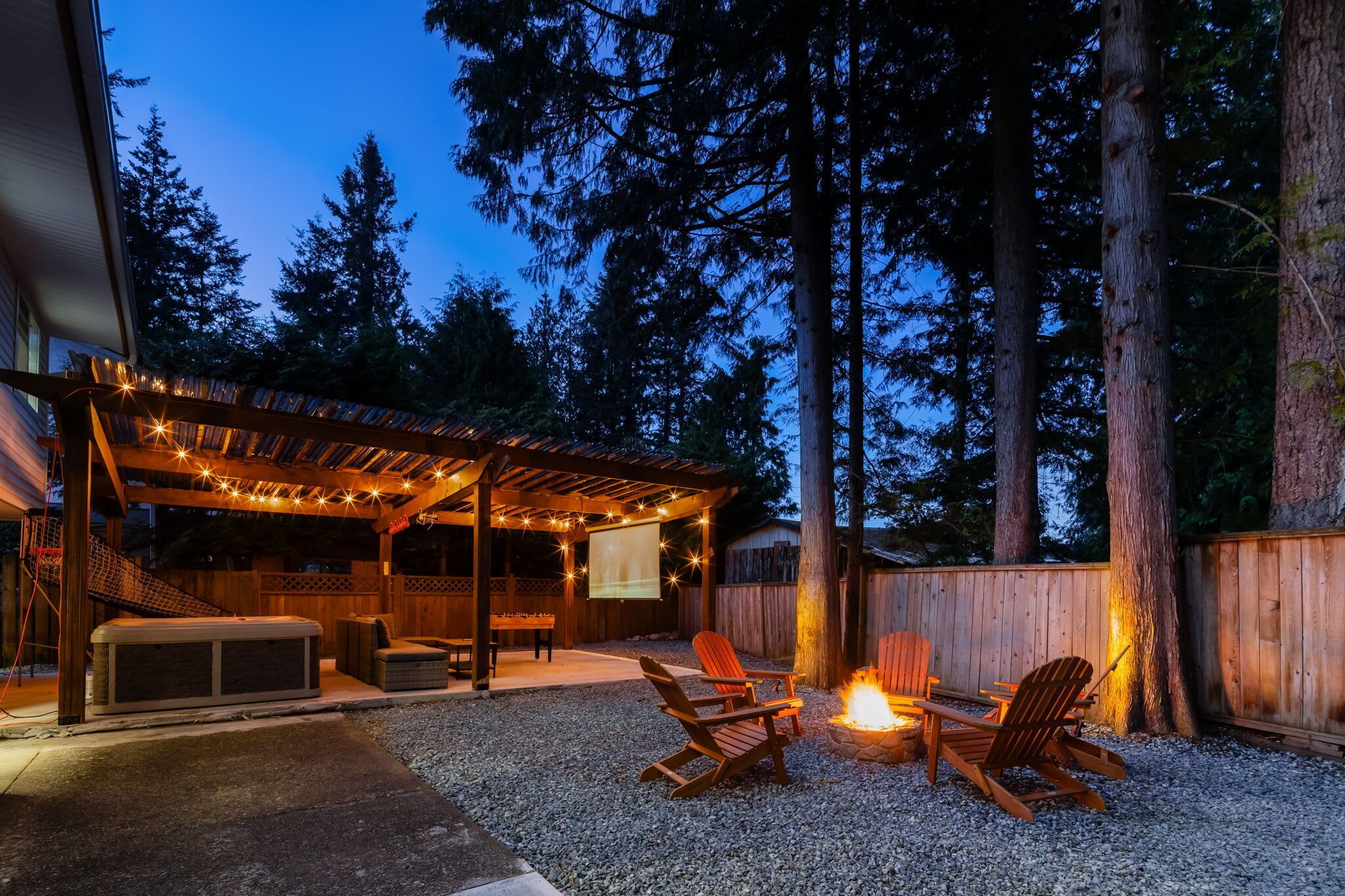 Un patio extérieur couvert avec un jacuzzi, des sièges et un foyer.