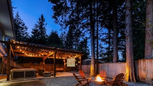 Un patio techado al aire libre con jacuzzi, asientos y una chimenea.