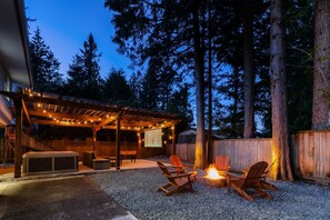 A covered outdoor patio with a hot tub, seating, and a fire pit. - Bunny Bliss - Lower Level, HotTub, FirePit,Theatre (Langley)