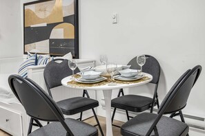 A dining area with a round table, four chairs, and a white wall with a painting. - Bunny Bliss - Lower Level, HotTub, FirePit,Theatre (Langley)