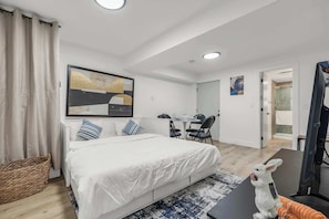 A modern hotel room with a large bed, a desk, and a chair, a small table, and a decorative rabbit figurine. - Bunny Bliss - Lower Level, HotTub, FirePit,Theatre (Langley)