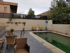 Ein Pool mit Korbmöbeln und Blumentöpfen.