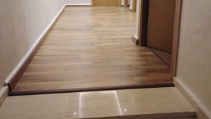 A hallway with a wooden floor, a door at the end, and a small step leading to a tiled area. - Pleasant family stay in a superb villa (Tassoultante Marrakech)