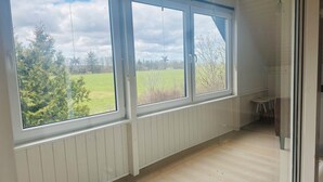 A room with large windows, a wooden floor, and a view of a green field. - Family private house 4-5 rooms (Brovst)