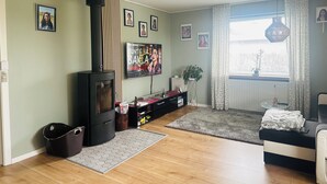 A living room with a wood-burning stove, a television, and framed pictures on the wall. - Family private house 4-5 rooms (Brovst)