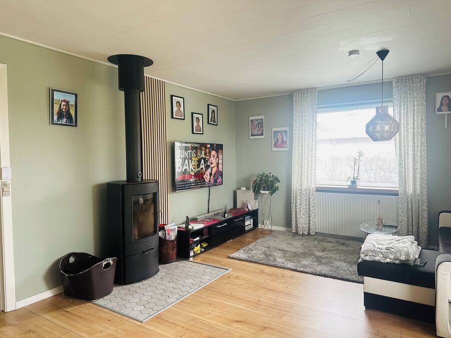 A living room with a wood-burning stove, a television, and framed pictures on the wall.