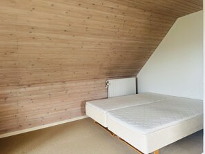 A room with a sloped ceiling, wooden walls, a mattress, and a radiator. - Family private house 4-5 rooms (Brovst)