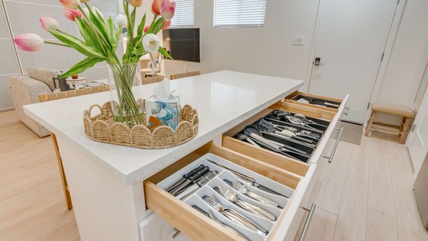 Uma cozinha moderna com uma ilha central, um vaso de tulipas e uma televisão de tela plana.