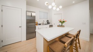 Uma cozinha moderna com ilha central, eletrodomésticos de aço inoxidável e uma luminária pendente.