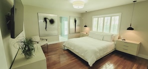 A modern bedroom with a large bed, bedside tables, a TV, and abstract art on the walls.