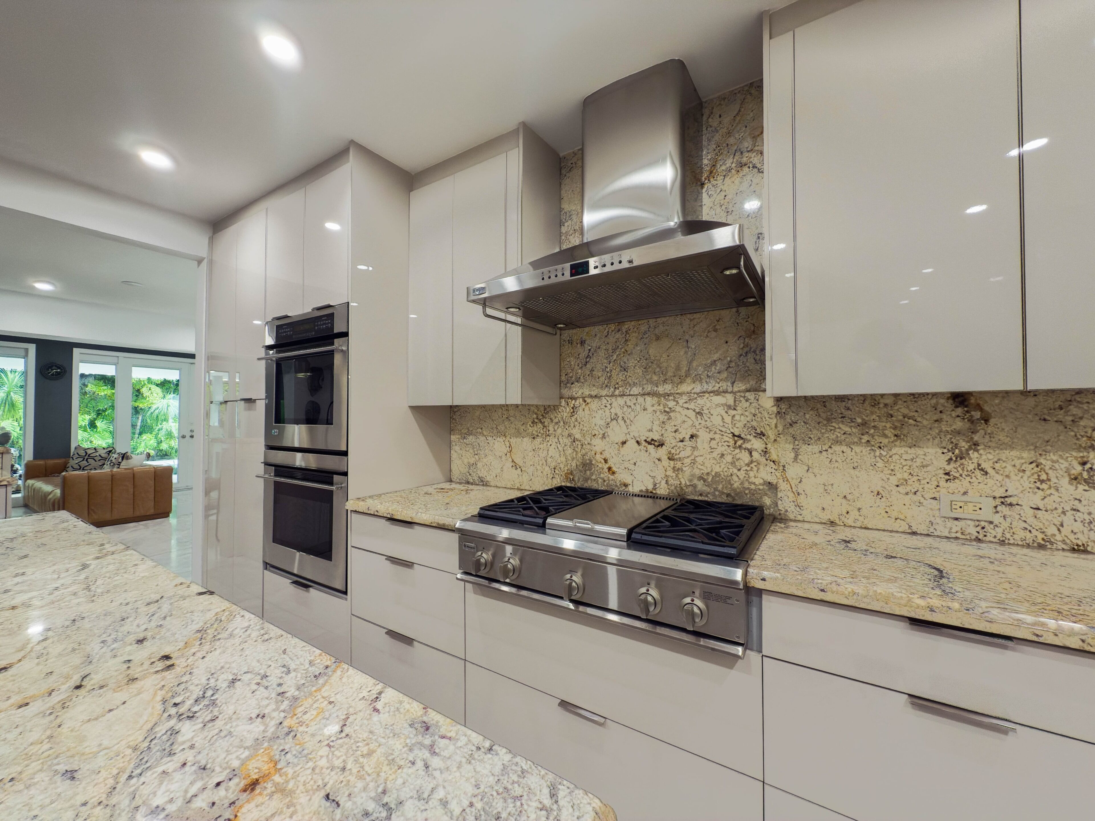 A modern kitchen with stainless steel appliances, marble countertops, and a view of the outdoors.