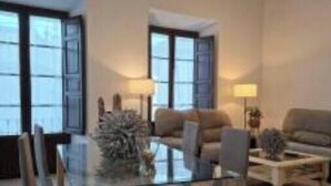 A modern living room with a glass dining table, two sofas, and a coffee table.