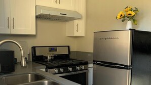Cuina amb armaris blancs, nevera d'acer inoxidable, fogó i rentapelats.