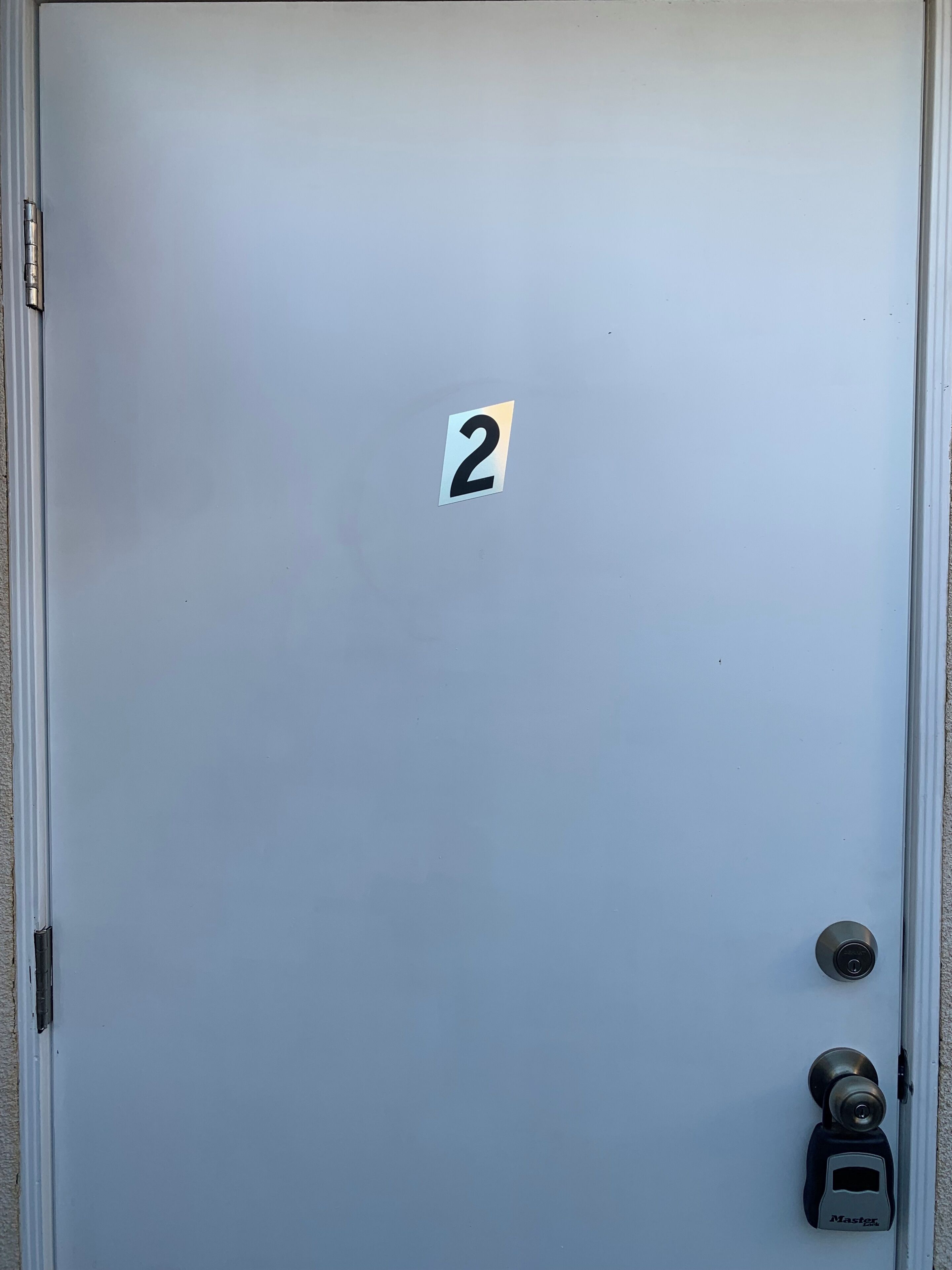 Una porta amb un adhesiu amb el número 2, un ull de cerradura i un timbre etiquetat 'Master'.