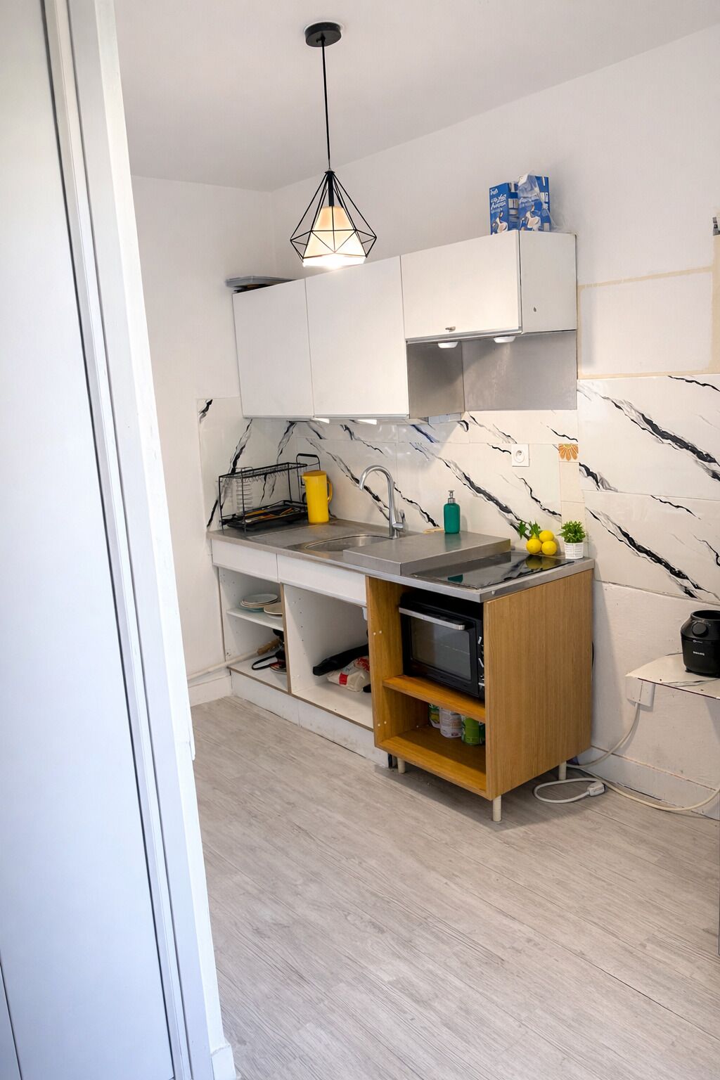 A modern kitchen with white cabinets, a marble backsplash, and a wooden island.