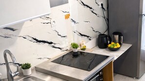 A modern kitchen with a built-in stove, a sink, a refrigerator, and a blender on the counter. - Apartment with swimming pool, janitor and parking space (Mandelieu-la-Napoule)