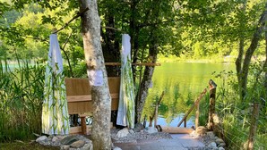 Eine Holzterrasse mit einer Bank, umgeben von Steinen und Kieselsteinen, die zu einem See führt.