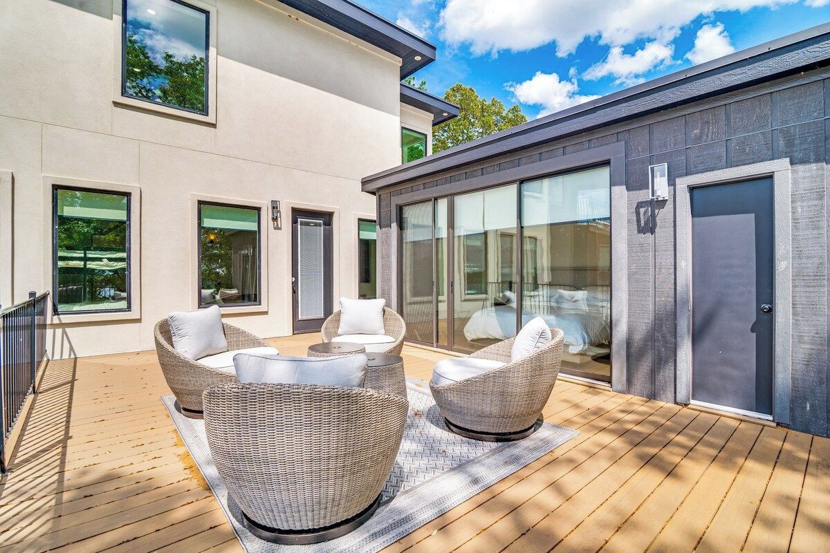 Une terrasse extérieure moderne, dotée de meubles en osier et d’une plateforme en bois.