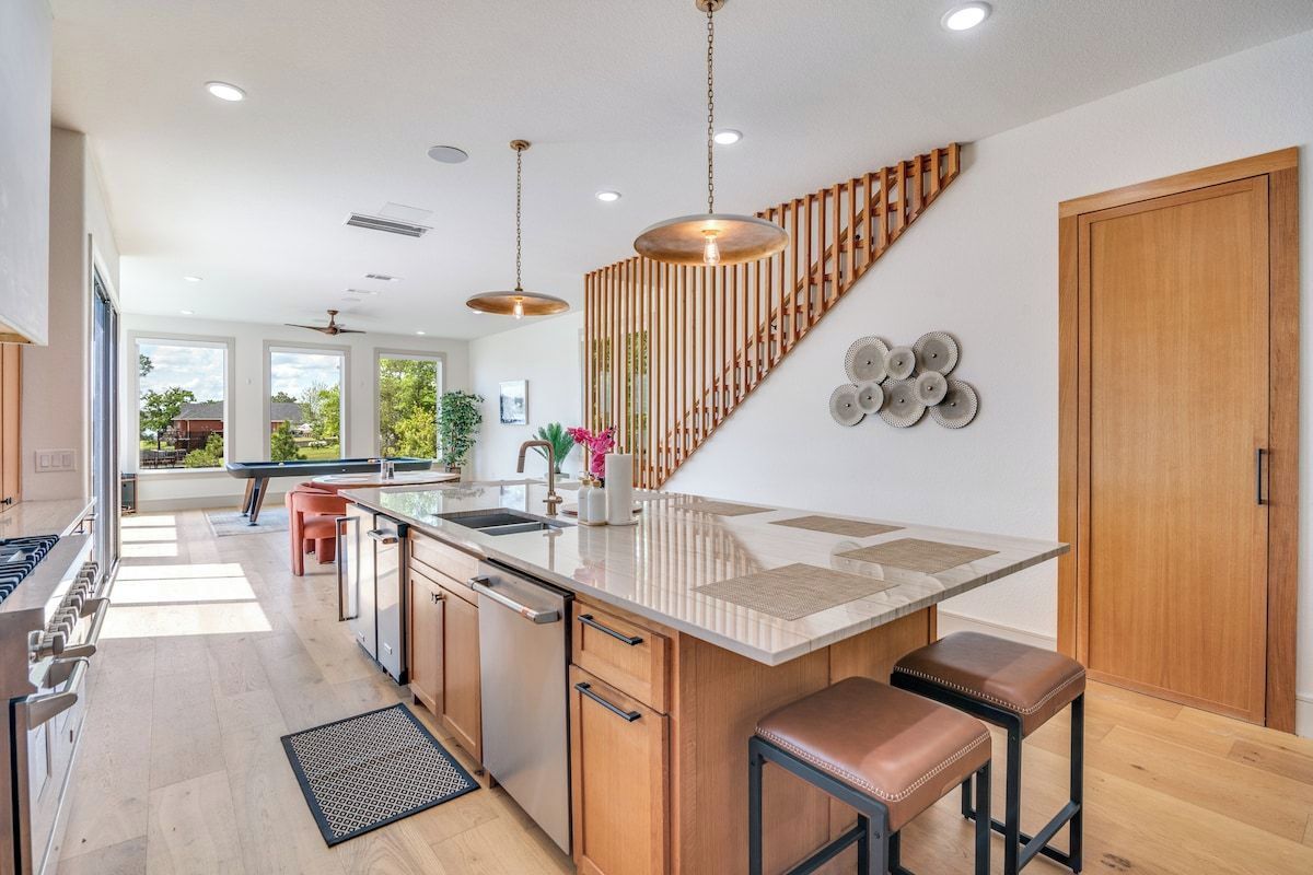 Una cocina moderna con una isla central, armarios de madera e iluminación colgante.