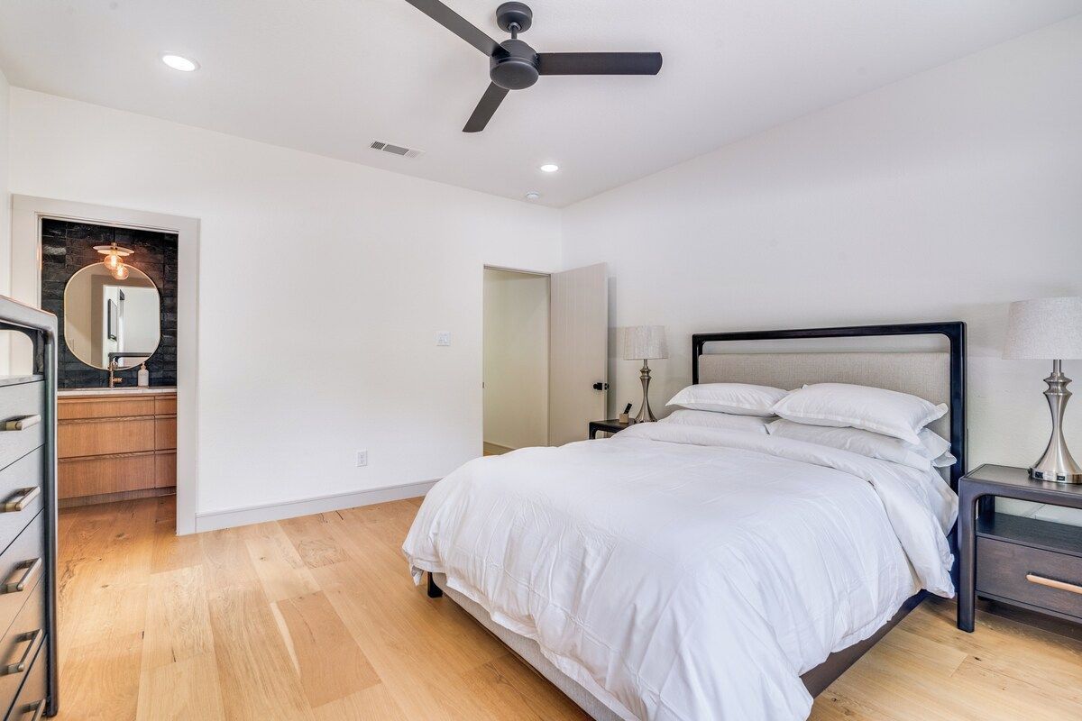 Un dormitorio con cama, mesita de noche, lámpara y ventilador de techo.