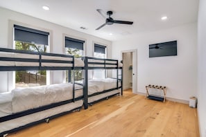 Habitació amb llits superposats, ventilador de sostre i televisió penjada a la paret.